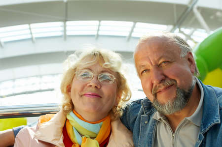 Seniors sitting and smiling in a modern interior with a glass roofの写真素材