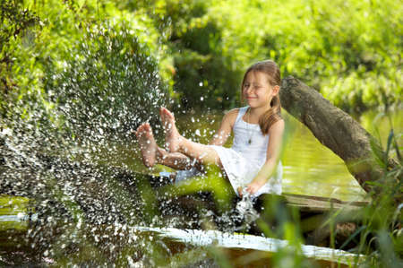 The playful girl sprays feet pond water  の写真素材