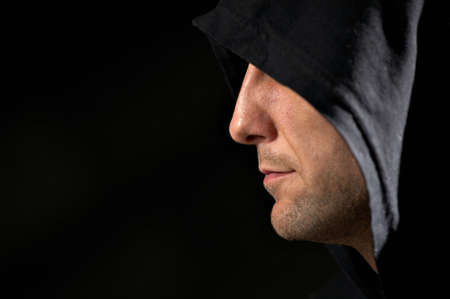 Profile of the man in a hood on a black background      の写真素材