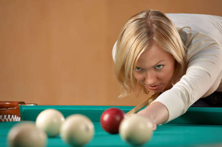 The beautiful blonde aims to a sphere in billiards