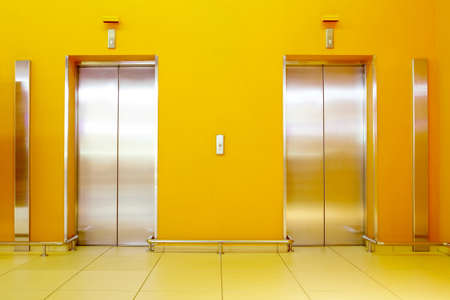 Photo of an orange hall with two liftsの写真素材