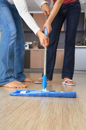 Two people are cleaning the house with one and the same mopの写真素材