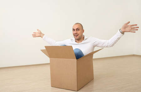 A man is sitting in an empty box in a new flatの写真素材