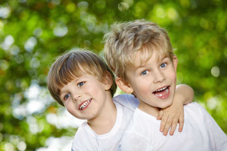 Two cheerful boys embrace in a summer gardenの写真素材