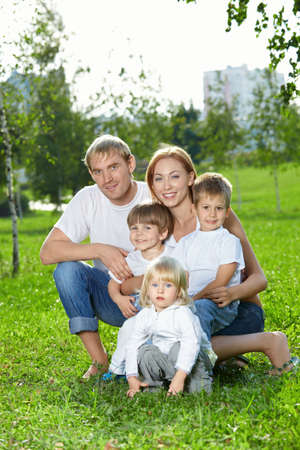 Young family for five persons, has a rest in a summer gardenの写真素材