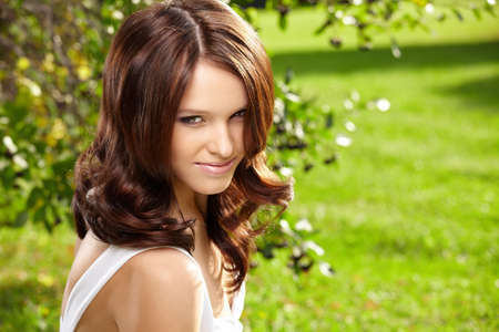 Portrait of the delightful curly young woman in a summer gardenの写真素材