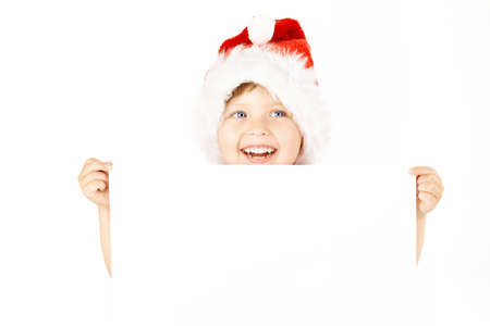 Laughing little boy in a suit of santa shows the blank sheet, isolatedの写真素材