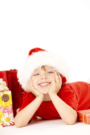Little santa lies near to the gift boxes, isolatedの写真素材