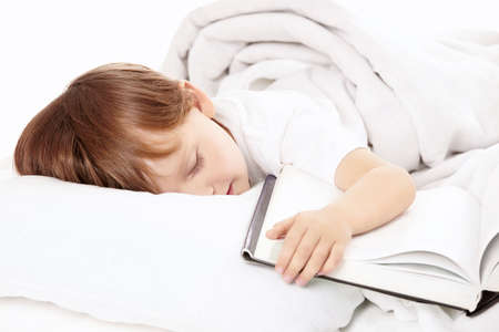 Little boy sleeps in bed embracing the book, isolatedの写真素材