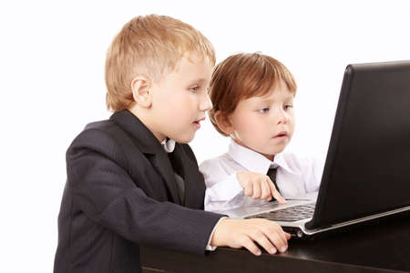 Two little boys in business suits together look in the screen of the laptop, isolated
の写真素材
