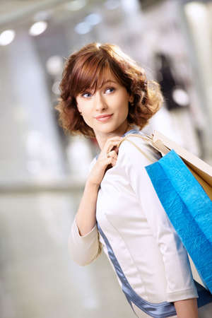 Portrait of girl standing in a half-turn with packages in shopの写真素材