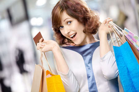 Portrait of the young beautiful woman smiling in shop with bags and a credit cardの写真素材