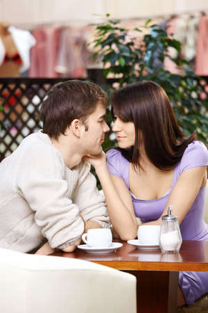 Loving couple talks behind a little table in cafeの写真素材