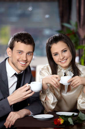Happy smiling couple in cafe with cups in handsの写真素材