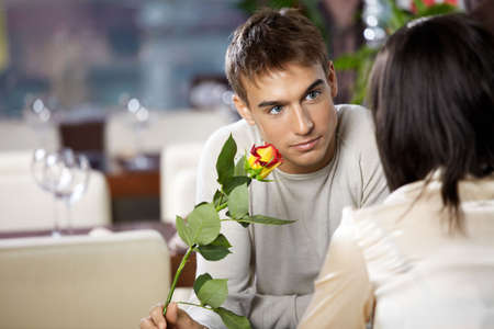 Pair in cafe - man gives to woman a flowerの写真素材