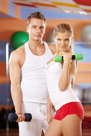 Girl and the man with dumbbells in hands in sports clubの写真素材
