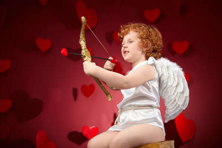 Little boy in an image of the cupid on a red backgroundの写真素材