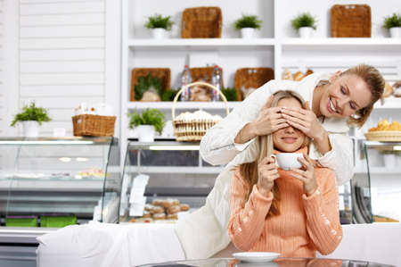 The young girl closes eyes to the girlfriend in cafeの写真素材