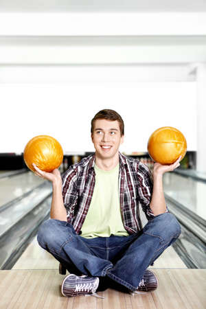The young guy with two spheres for bowling in a yoga pose
の写真素材