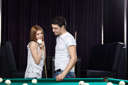 The attractive girl shows to the young man a billiard sphere