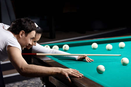 The young couple aim before blow in billiards