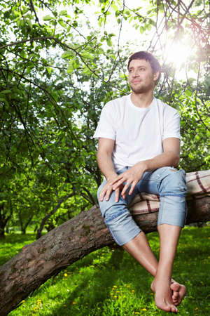 The young man sits on a treeの写真素材
