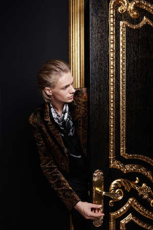 The man inserts a key into a keyhole of a black-gold doorの写真素材