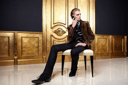 The young man speaks by phone in a gold interiorの写真素材