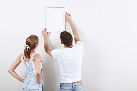 Young couple hangs framed on the wallの写真素材