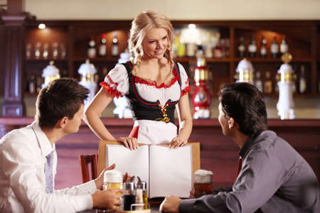 Attractive waitress shows visitors the menu barの写真素材