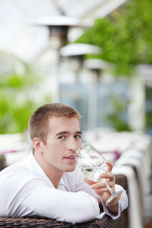 Young man drinking water at a restaurantの写真素材