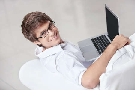 A young man with a laptop on a couch