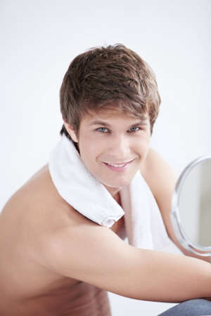 A young man with a towel in the mirrorの写真素材