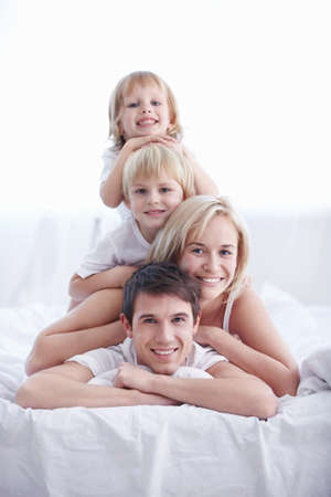 Smiling family on a white bedの写真素材