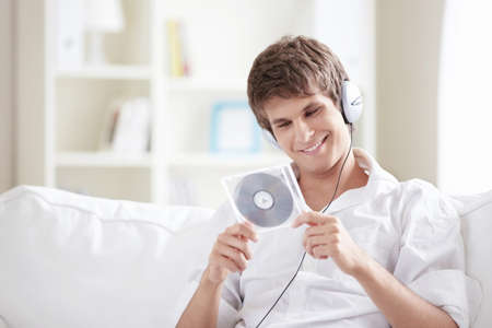 A young man with headphones and music CDs into the hands ofの写真素材
