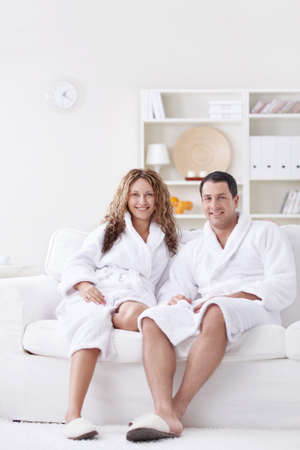 Attractive happy couple in robes at homeの写真素材