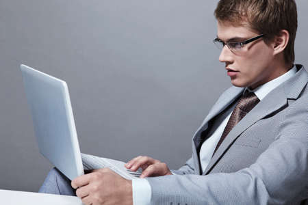 A young man in a suit with a laptopの写真素材