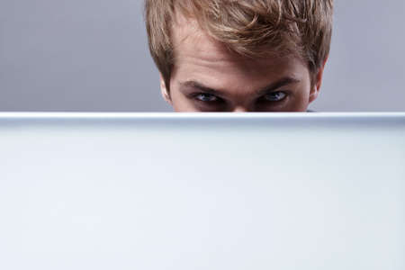 Young attractive man looks out for the laptopの写真素材