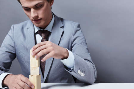 Attractive businessman to build a tower on a gray backgroundの写真素材