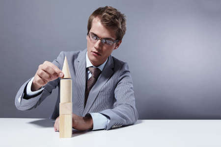 A young businessman to build a tower on a gray backgroundの写真素材
