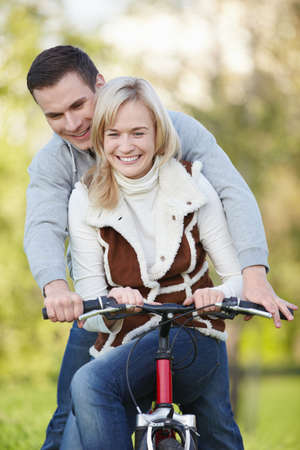 Young couple rides a bicycle in the parkの写真素材