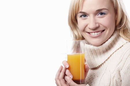 A woman in a sweater with a glass of juice on a white backgroundの写真素材