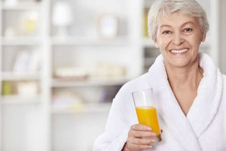 Happy elderly woman with a glass of juiceの写真素材