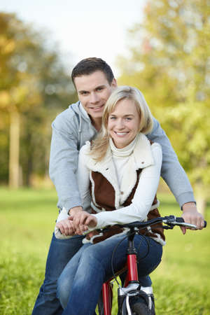 Attractive young couple on a bicycle in the parkの写真素材