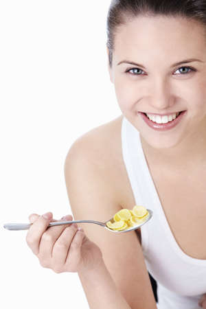 Young attractive woman holding a spoonful of corn flakes on a white backgroundの写真素材