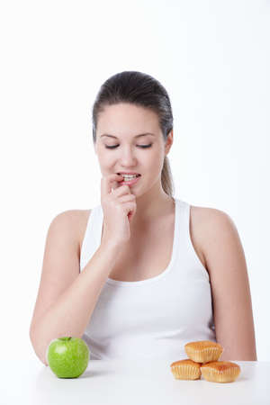 A young girl chooses between a healthy diet and sweet on a white backgroundの写真素材