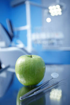 Apple and dental instruments in the foregroundの写真素材