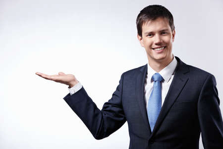 A young businessman shows his hand towardsの写真素材