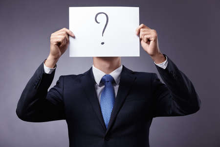 Businessman in suit holding a sign with a question markの写真素材