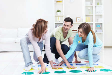 Young happy people playing twister at homeの写真素材